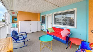Una habitación con un sofá azul, una mecedora, una mesita y una ventana con persianas.