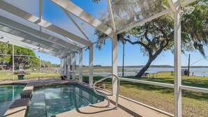 Un área de piscina techada con vista a un lago y árboles.