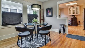 Un coin repas avec une table en verre, des chaises noires, un lustre, une échelle et un meuble avec des portes en verre.