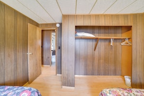 Une chambre avec des murs en bois, un lit, une armoire et un dressing.