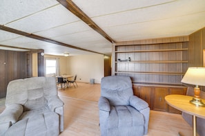 A spacious room with two armchairs, a wooden wall unit, and a small table with a lamp. - Outdoor Adventure Base in the Heart of Miller (Miller)