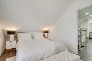 Un dormitorio con una cama grande, lámparas de noche, una mesita de noche y un espejo.