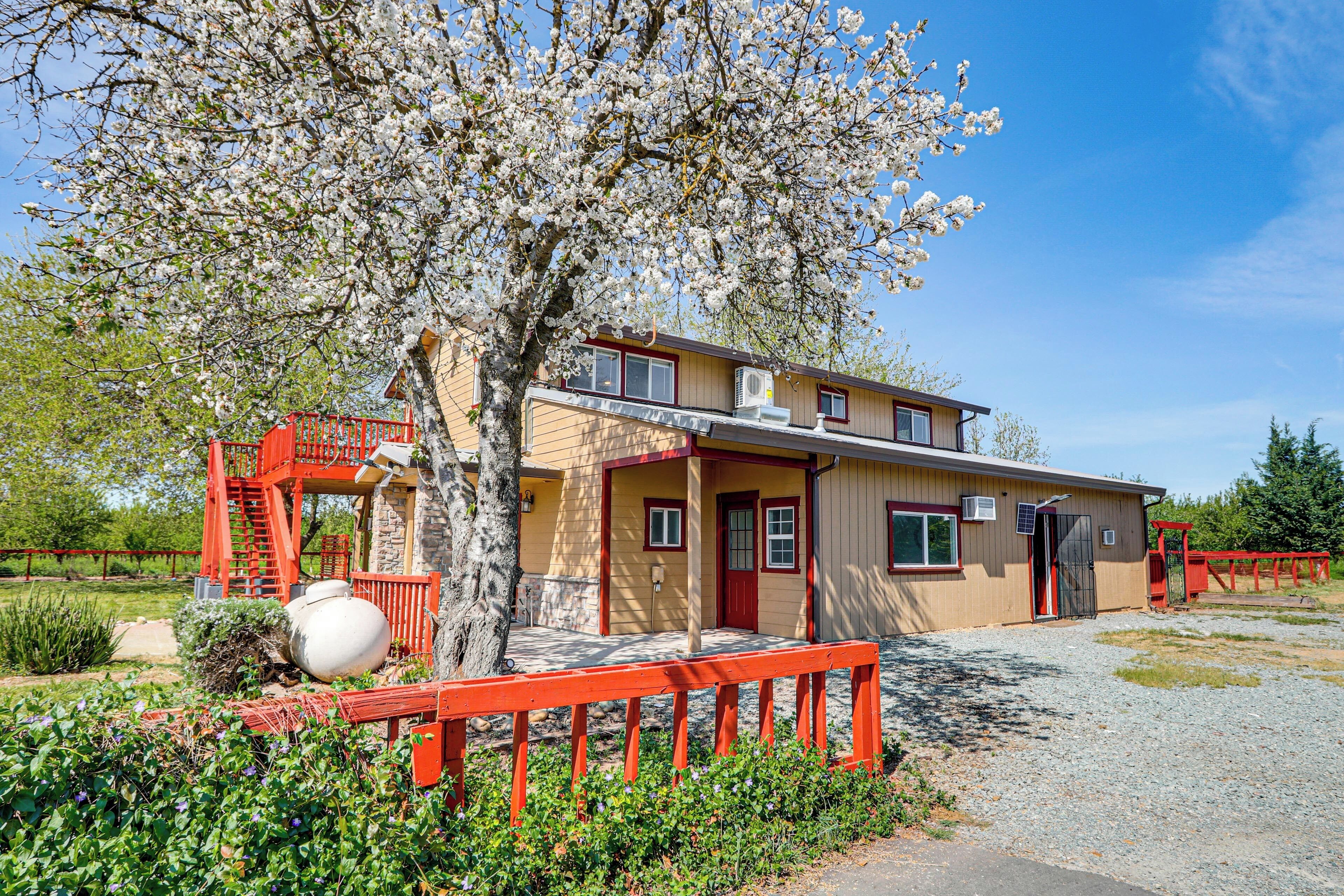 Un bâtiment à deux étages, à la façade rouge, doté d’un porche abrité et d’un arbre aux fleurs blanches devant l’entrée.