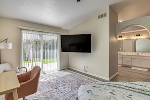A modern living room with a flat-screen TV, a sofa, a coffee table, and a patterned rug. - Spring Valley Lake Home w/ Desk & Fenced Yard (Victorville)