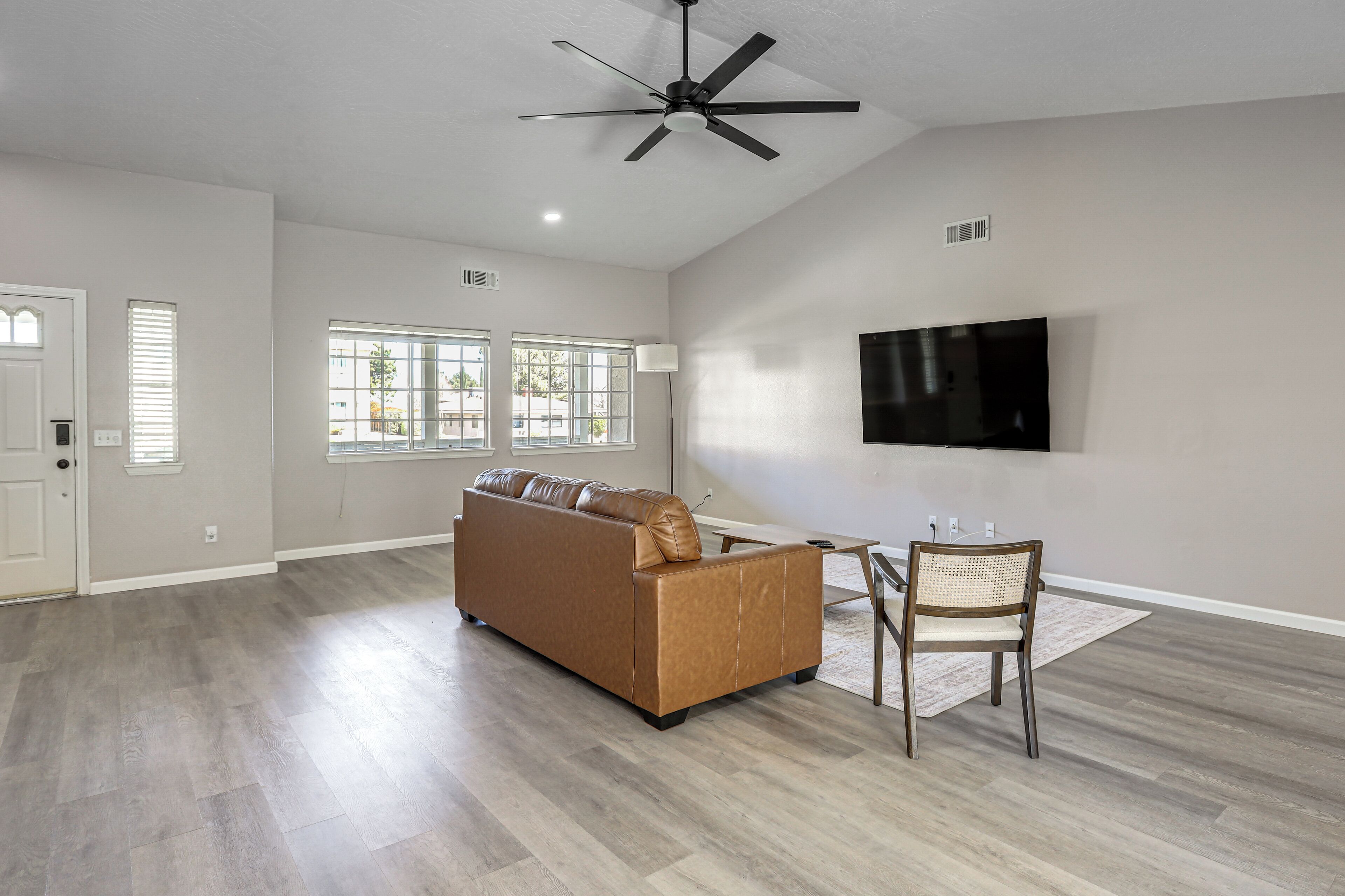 A living room with a sofa, a TV mounted on the wall, and a ceiling fan.