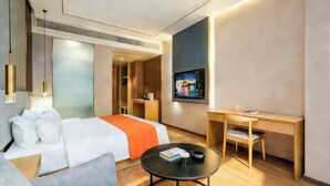 A modern hotel room with a bed, a desk, a chair, a coffee table, and a TV mounted on the wall. - spiderHotel (Hangzhou)