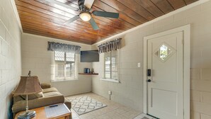 A room with a ceiling fan, a door with a diamond-shaped window, a couch, a table with a lamp, and a patterned rug. - Lake Days + Pool Fun! Nature Coast Retreat (Hernando)