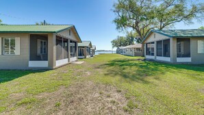 A row of single-story buildings with a green roof, a grassy area in front, and a large tree to the right. - Lake Days + Pool Fun! Nature Coast Retreat (Hernando)