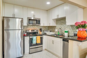 Una cocina moderna con gabinetes blancos, electrodomésticos de acero inoxidable y un salpicadero de azulejos.
