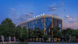 A modern hotel building with a glass facade and a sign indicating it is a hotel. - spiderHoteOne (Hangzhou)