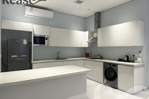 A modern kitchen with white cabinetry, a built-in washing machine, and a stainless steel refrigerator. - Kease Ar Rabi J-1 Royal Touch GX69 (Riyadh)