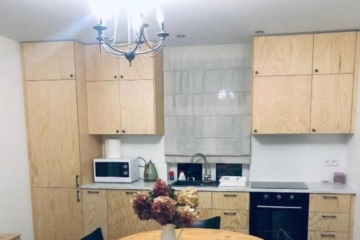 Eine kompakte Küche mit Holzschränken, einer zentralen Kochinsel mit Stühlen, einer Mikrowelle und einem Spülbecken.