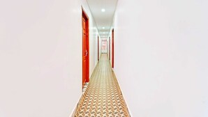 A long, narrow hallway with patterned flooring and red doors on both sides.