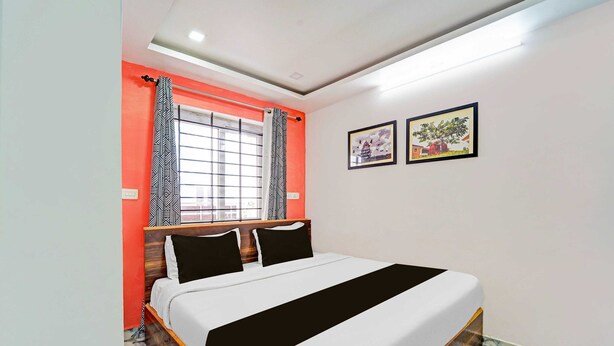 A bedroom with a bed, curtains, a window with a view, and two framed pictures on the wall.