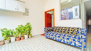 A room with a patterned floor, a sofa, potted plants, a cabinet, and a door.