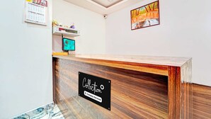 A reception desk with a wooden finish, a company service sign, a calendar, and a framed landscape painting on the wall.