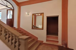 A staircase with a handrail, a wall-mounted mirror, and a door leading to another room. - Apartment in a village with swimming pool (Pesaro)