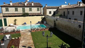 Ein Innenhof mit Swimmingpool, Sitzgelegenheiten im Freien und Steinbauten.