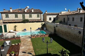 Un patio con piscina, mobiliario exterior y edificios de piedra.