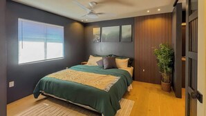 A bedroom with a bed, a ceiling fan, a window, and a potted plant.