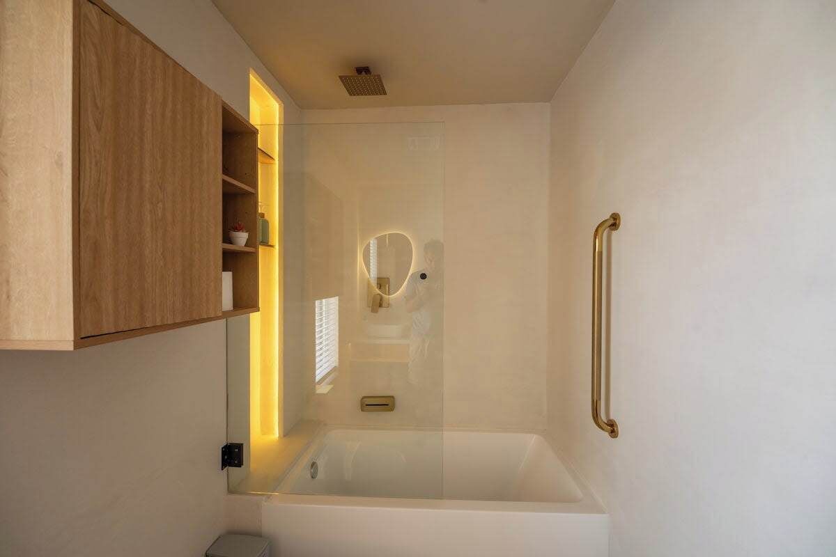 A modern bathroom with a bathtub, a wooden cabinet, and a glass shower enclosure.