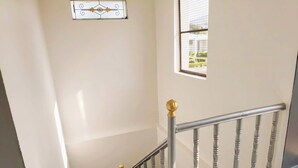 Eine Treppe mit Metallgeländer und Holzspindeln, die zu einem Raum mit Fenster und Wanddekor führt.