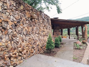 A stone wall, a covered wooden structure, and a pathway leading to a scenic view.