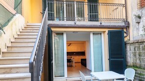 A residential building with a staircase leading to a balcony, a sliding glass door entrance to a kitchen, and a small outdoor seating area with a table and chairs. - Apartment a few minutes from the sea (Fano)