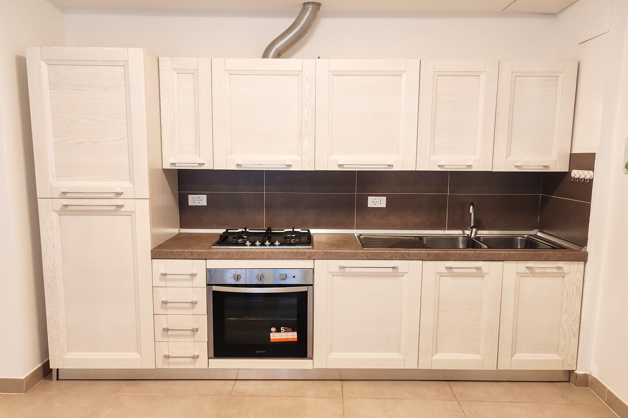 A kitchen with white cabinets, a stove, oven, and a sink.