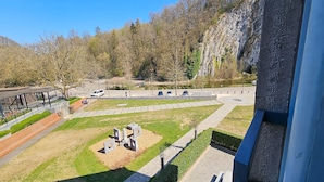 A view of a parking area with cars, a grassy area with sculptures, and a rocky hillside in the background.