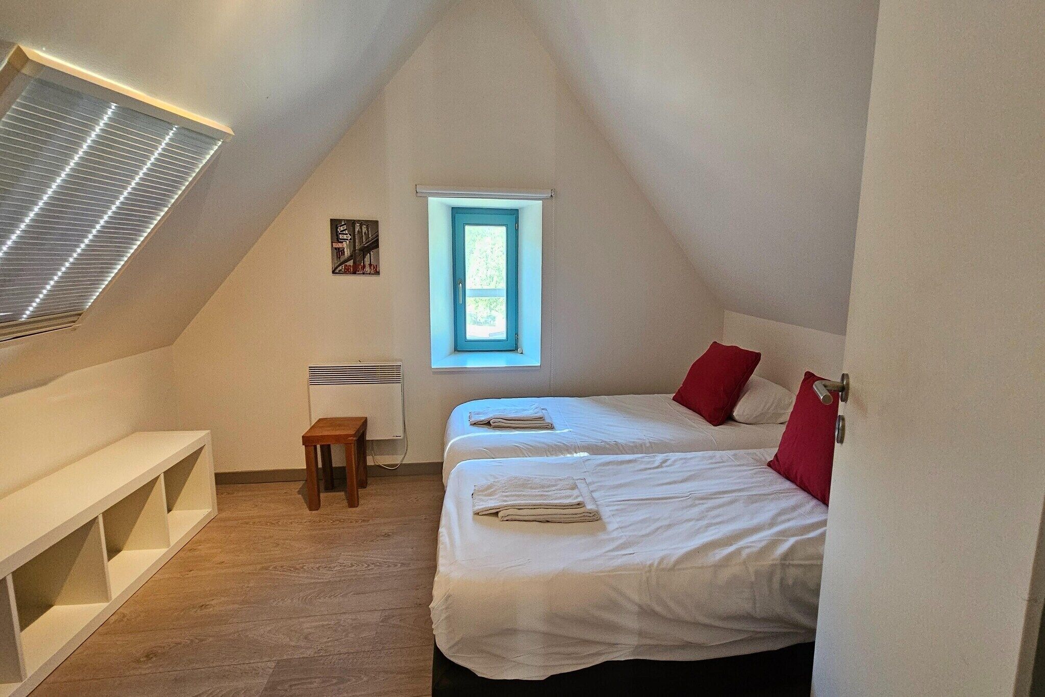 Ein kleines, dreieckiges Schlafzimmer im Dachgeschoss mit zwei Betten, einem Fenster, einer Heizung und einer Sitzbank.