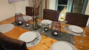 A dining table set with white plates, cutlery, glasses, and candle holders.