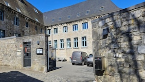 A stone building with a courtyard, a gate, and a parked van.