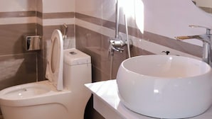 A bathroom with a toilet, a shower, a sink, and a mirror. - An Hotel (Sa Pa)