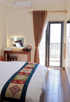 A hotel room with a bed, a desk with a mirror, a window with curtains, and a balcony view. - An Hotel (Sa Pa)