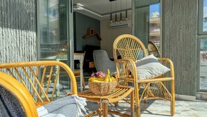 Ein modernes Interieur mit Korbstühlen, einem Korb voller Früchte und einer Glastür zu einem Außenbereich.
