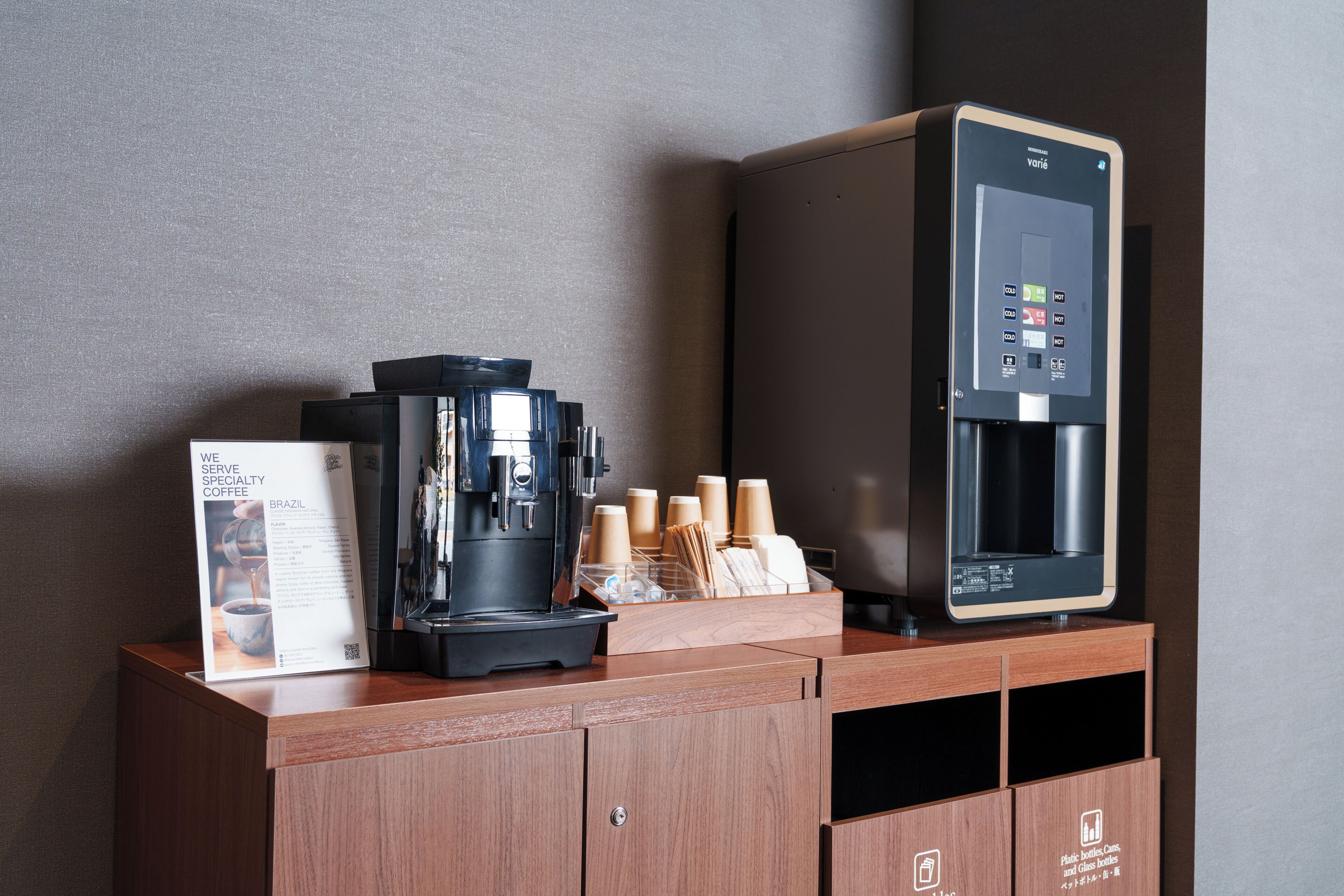 Una estación de café con una cafetera, un dispensador de agua y un atril para el menú.