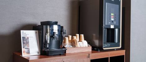 Una estación de café con una cafetera, un dispensador de agua y un atril para el menú.