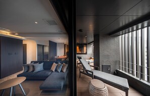 A modern interior with a sofa, lounge chairs, and a view through a glass partition. - KOHAKU Apartment Hotel Kyoto (Kyoto)