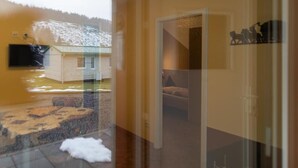 A room with a bed, a television, and a view of a snowy landscape through a glass door.