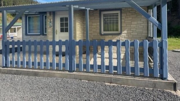 En etagers bygning med veranda og et plankeværk.