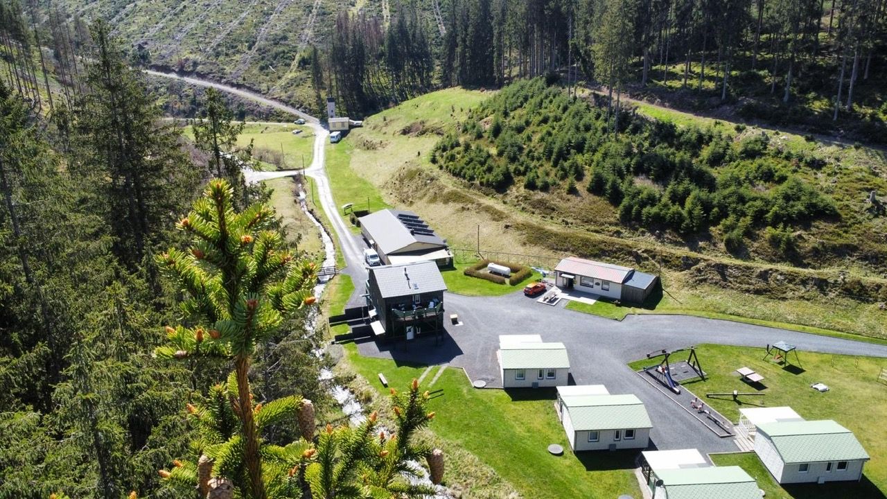A campground with multiple cabins, a central building, and a parking area.