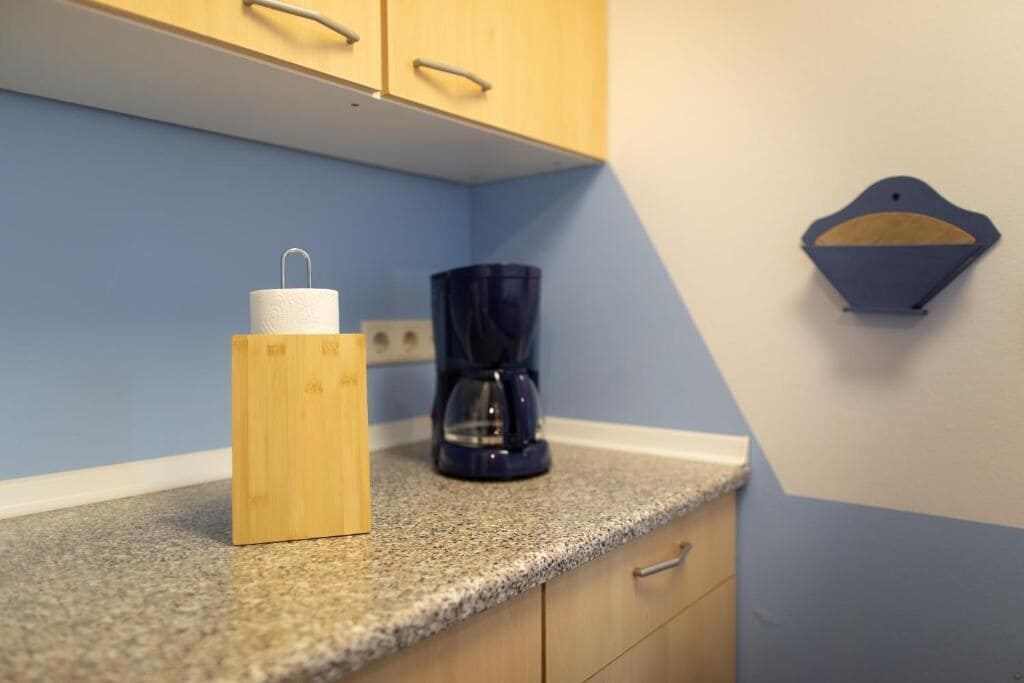Una cucina con un pensile in legno, una macchina da caffè e un porta asciugamani in carta sul piano di lavoro.