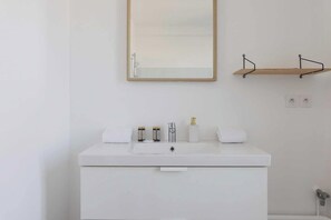A white bathroom with a wooden shelf above a white sink, a mirror, and a toilet. - Magnificent apartment -2BR-6P- Saint-Denis (Saint-Denis)