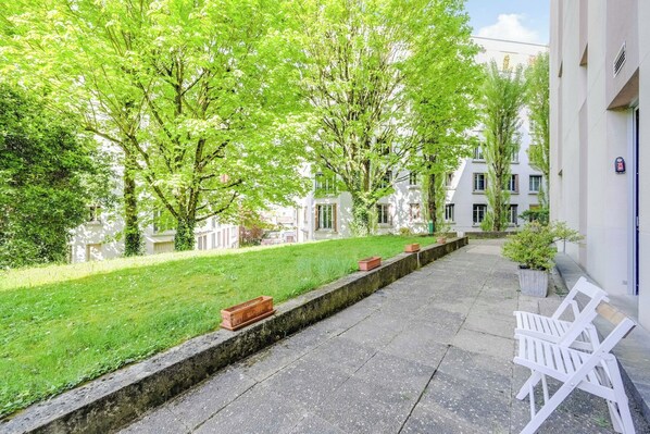 Ein Innenhof mit Bank, Weg und einem Gebäude mit Tür und Fenstern.