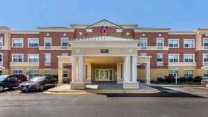 Un hotel a più piani con un ingresso centrale, numero 201, e un parcheggio con diverse automobili.