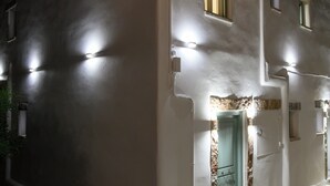 Un bâtiment blanc avec une porte verte, de nombreuses fenêtres et un éclairage extérieur.