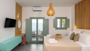 Une chambre d’hôtel moderne équipée d’un lit, d’une télévision, d’un coin salon et offrant une vue à travers la porte.