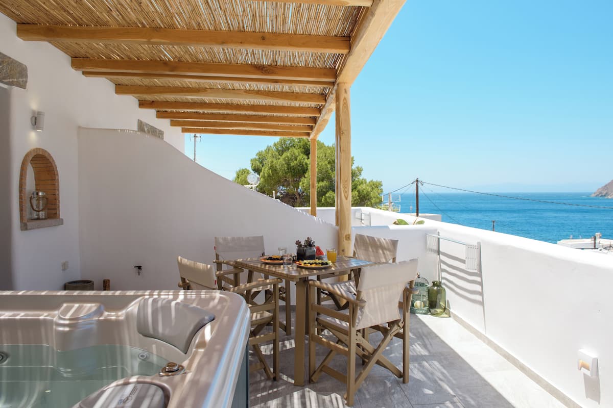 Terraço com hidromassagem, mesa de jantar e cadeiras, com vista para a costa.