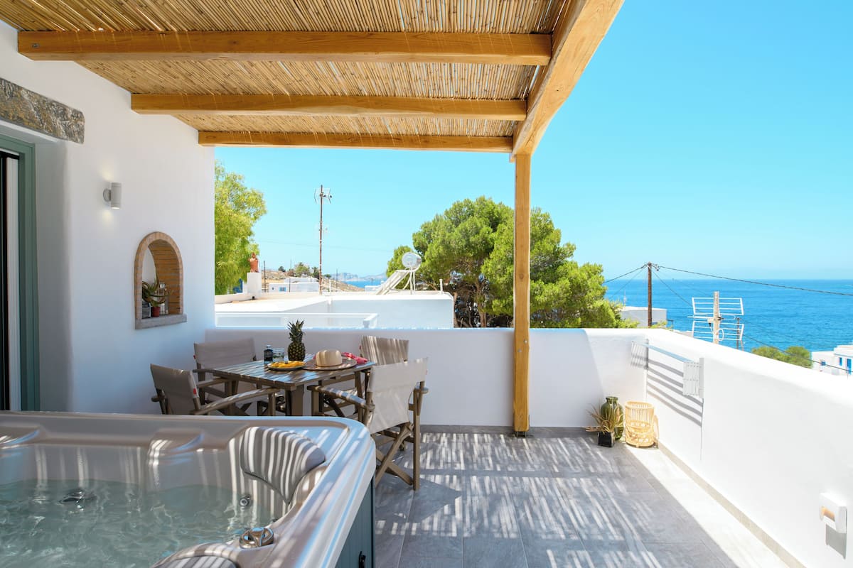 Terraço no telhado com hidromassagem, área de refeições e vista para o mar.